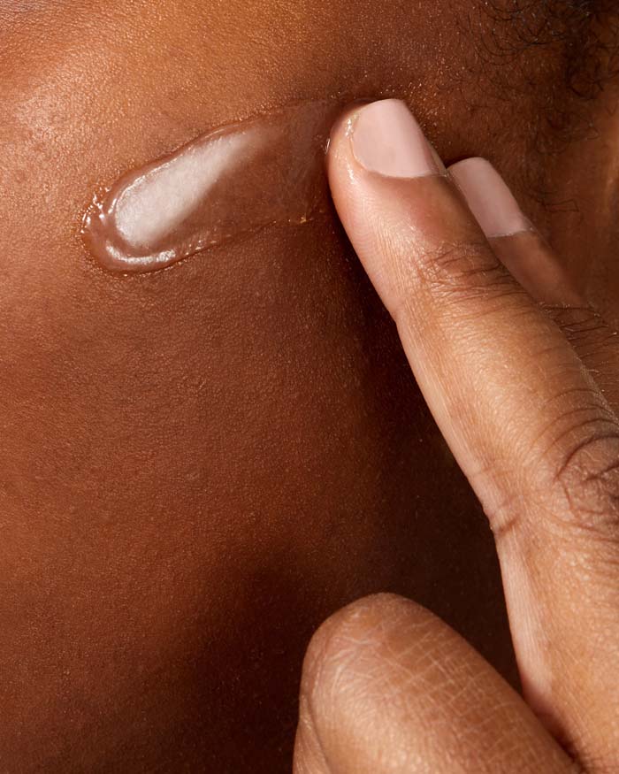 Close up of a woman applying hyaluronic acid serum to her cheek